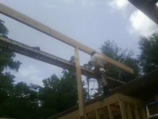 Carpenter setting a ridge beam over a new addition frame — Ice Dam Removal by Roofing Brothers in Saint Marys