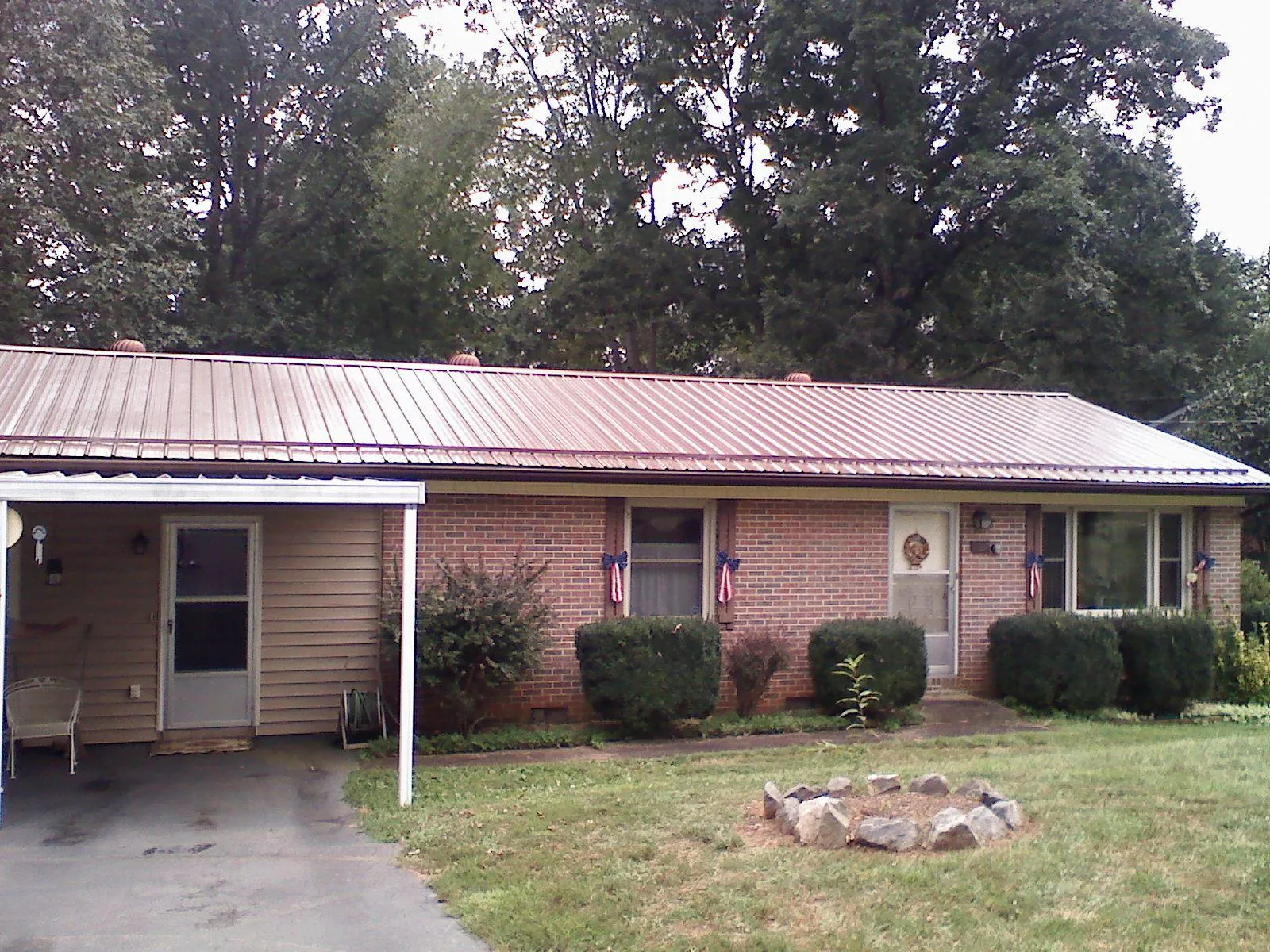 Bronze metal roof and carport on a brick ranch home — Roof Repair work by our crew in Saint Marys